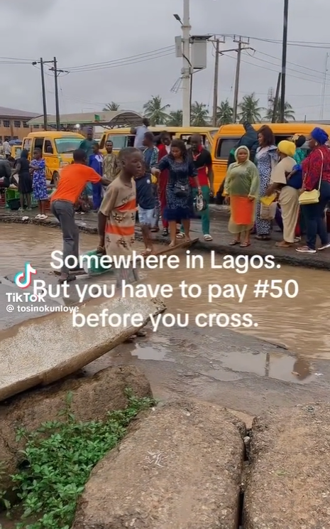 Video from an alleged Lagos bus stop where people have to pay N50 to cross a flooded gutter with a makeshift bridge